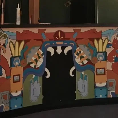 Aztec-style painted mural framing a doorway inside La Familia